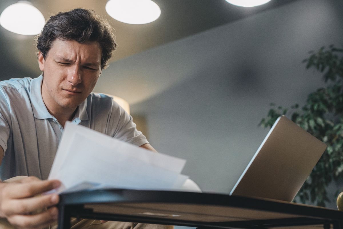 Professional reviewing documents on a laptop while considering work quality and responsibility